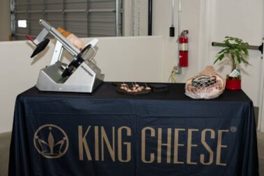 King Cheese table cloth draped over a table with cheese cutter on it.