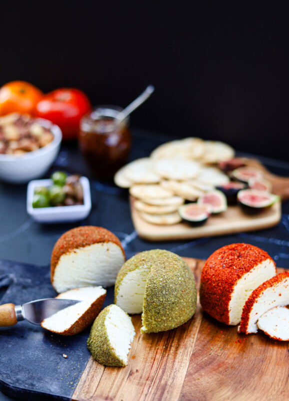 Feta cheese cut up with crackers and fruit blurred in the background.